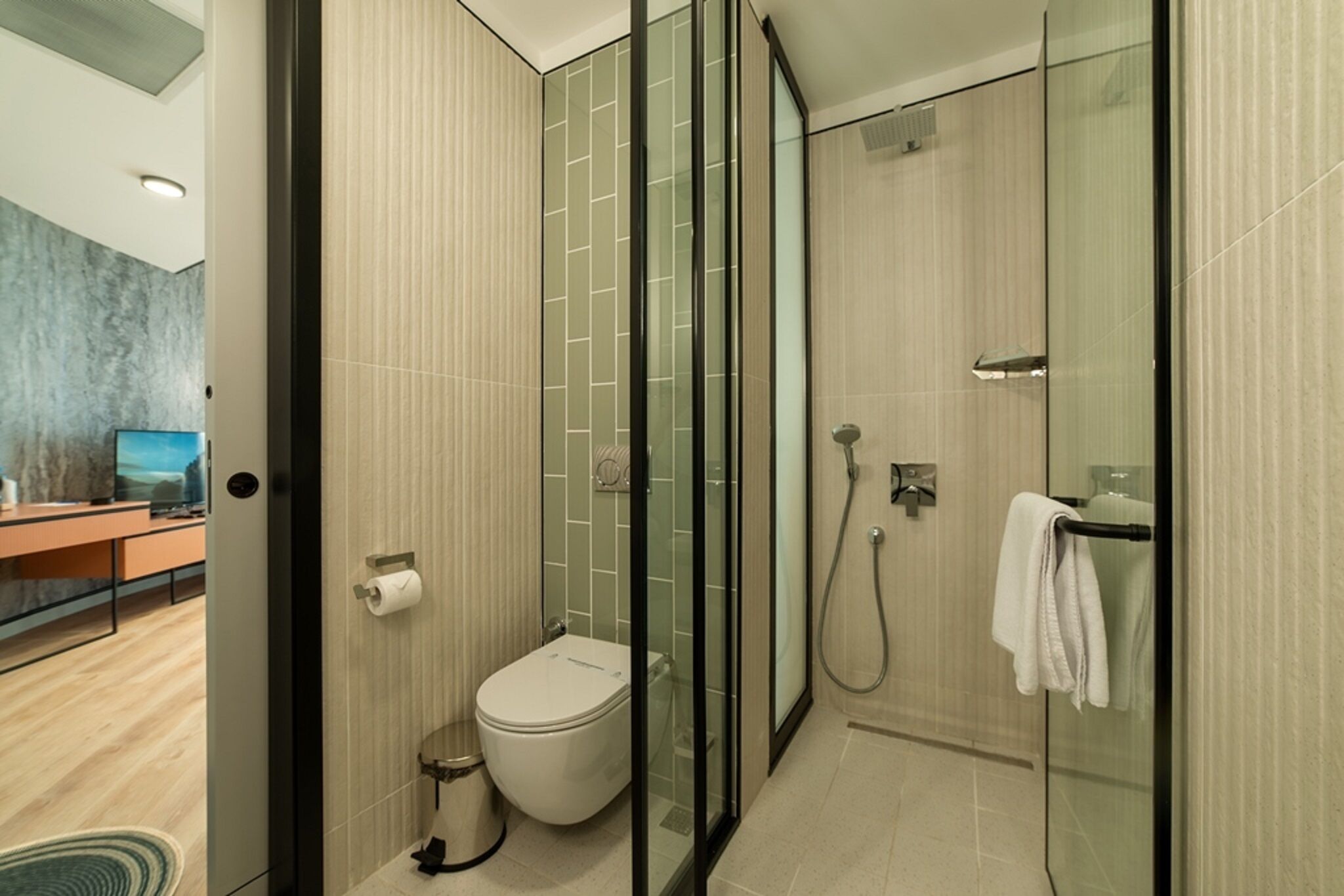 A modern bathroom with a glass shower enclosure, a toilet, and a glass door leading to a shower area.