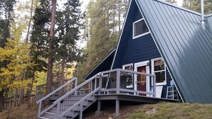 A house with a steeply pitched roof, a staircase leading to a deck, and a window. - Mountain Bliss is a quiet mountain retreat, sleeps 6, hot tub, pet friendly (Evergreen)