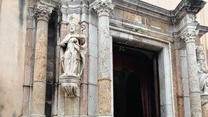Eingang eines historischen Gebäudes mit klassischen Säulen und einer Statue.