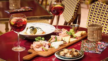 Una mesa de comedor con una selección de quesos, embutidos y una copa de vino tinto.
