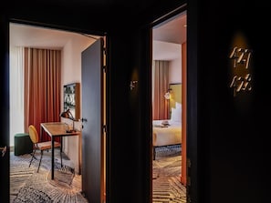 Hotellihuone, jossa on sänky, työpöytä, tuoli ja näkymä ulos.