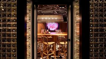 A room with a bar area, wicker chairs, and a patterned floor.