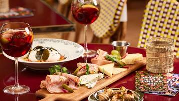 A table with a variety of food items including cheese, cured meats, and a glass of red wine.
