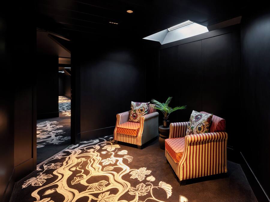 A dark room with two striped armchairs, a small table, and a potted plant.
