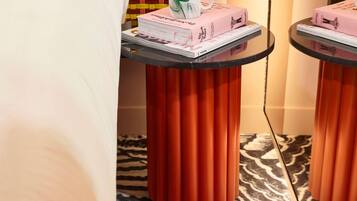 Una habitación con una alfombra estampada con diseño de cebra, una mesa con una pila de libros y una taza, y un par de zapatos en el suelo.