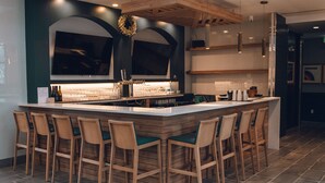 A modern kitchen with a large island, bar stools, and a decorative wreath on the wall.