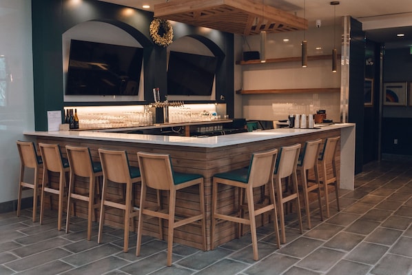 Une cuisine moderne dotée d’un grand îlot central, de tabourets de bar et d’une guirlande décorative accrochée au mur.