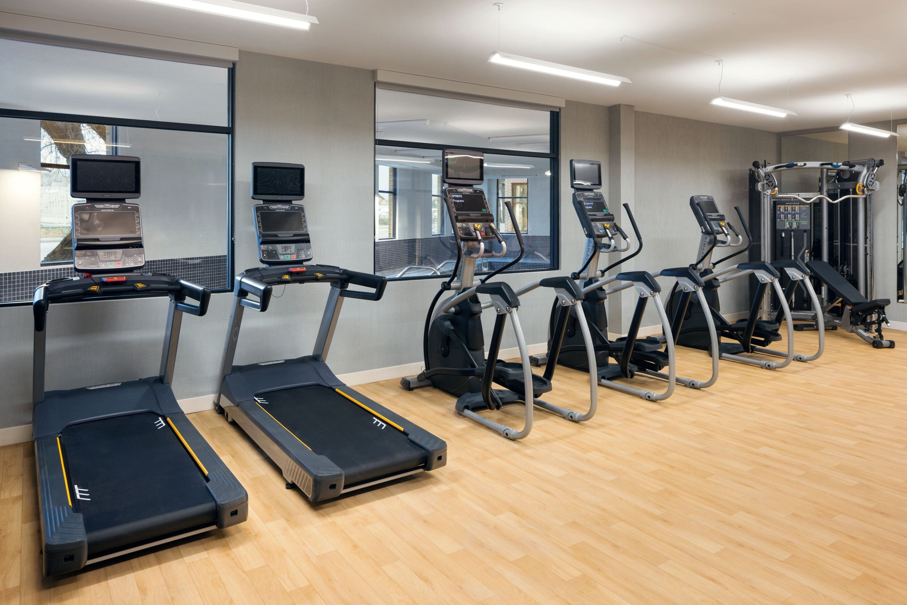 Un gimnasio con cintas de correr, elípticas y equipo de pesas.