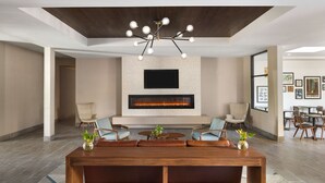 A spacious living area with a large wooden table, comfortable seating, a modern chandelier, a flat-screen TV, and a fireplace.