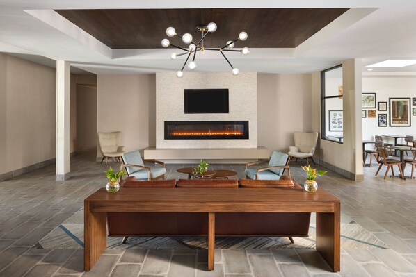 A spacious living area with a large wooden table, comfortable seating, a modern chandelier, a flat-screen TV, and a fireplace.