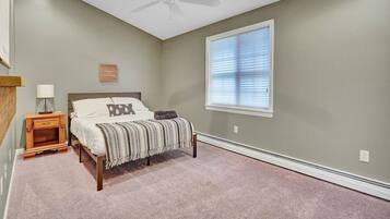 A bedroom with a bed, nightstand, lamp, and a ceiling fan.