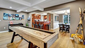 Une table de billard dans un grand salon, avec une cuisine et un coin repas en arrière-plan.
