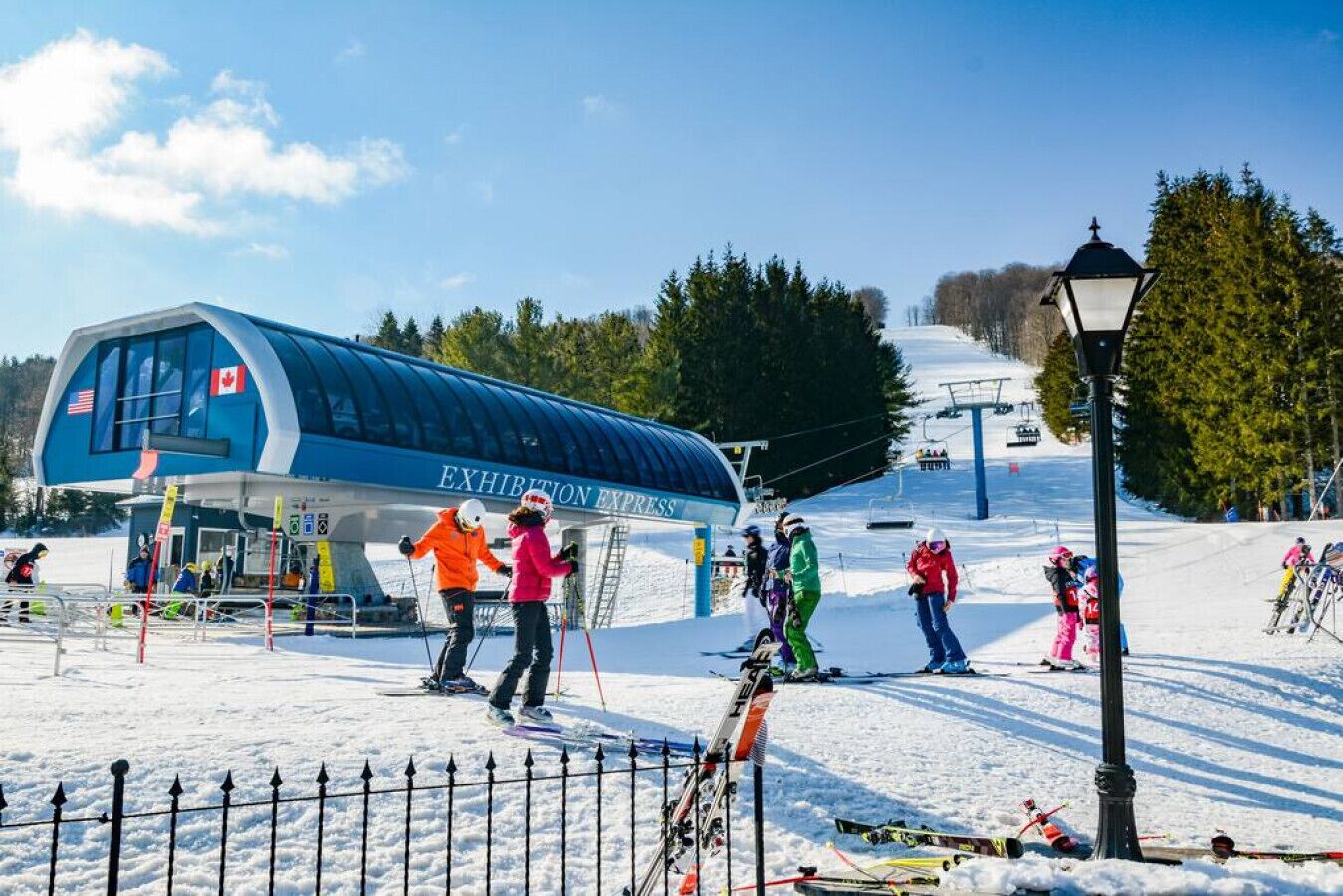 Une station de ski avec un bâtiment bleu portant l’inscription « EXHIBITION EXPRESS » et un télésiège en arrière-plan.