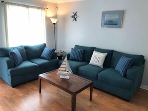 Relax in this inviting living area with a comfortable sofa arrangement and decorative sailboat model.