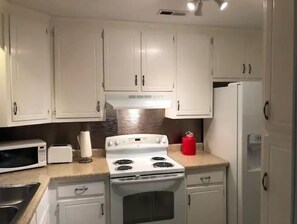 Efficient kitchen with a stove, sink, refrigerator, and microwave.
