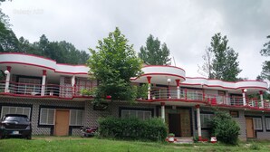 A multi-story building with balconies, a car, and a grassy area. - Banjosa Inn Guest House (Chhota Gala)