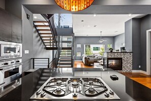 Una cocina moderna con una isla central, electrodomésticos de acero inoxidable y una escalera que conduce a un nivel superior.