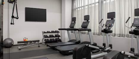 A gym with treadmills, elliptical machines, weight benches, and dumbbells.