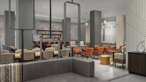 A modern library with bookshelves, seating areas, and a coffee bar. - SpringHill Suites by Marriott New York Queens (Long Island City)