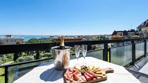A balcony with a table set for a meal, including a bottle of champagne, glasses, and a variety of cheeses and meats. - DesenzanoLoft Splendido  (Desenzano del Garda)