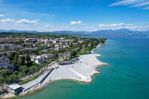 An aerial view of a coastal town with a beach, buildings, and mountains in the background. - DesenzanoLoft Splendido  (Desenzano del Garda)
