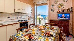 A kitchen with a dining table set for breakfast, a TV, and a view of the sea. - DesenzanoLoft Splendido  (Desenzano del Garda)