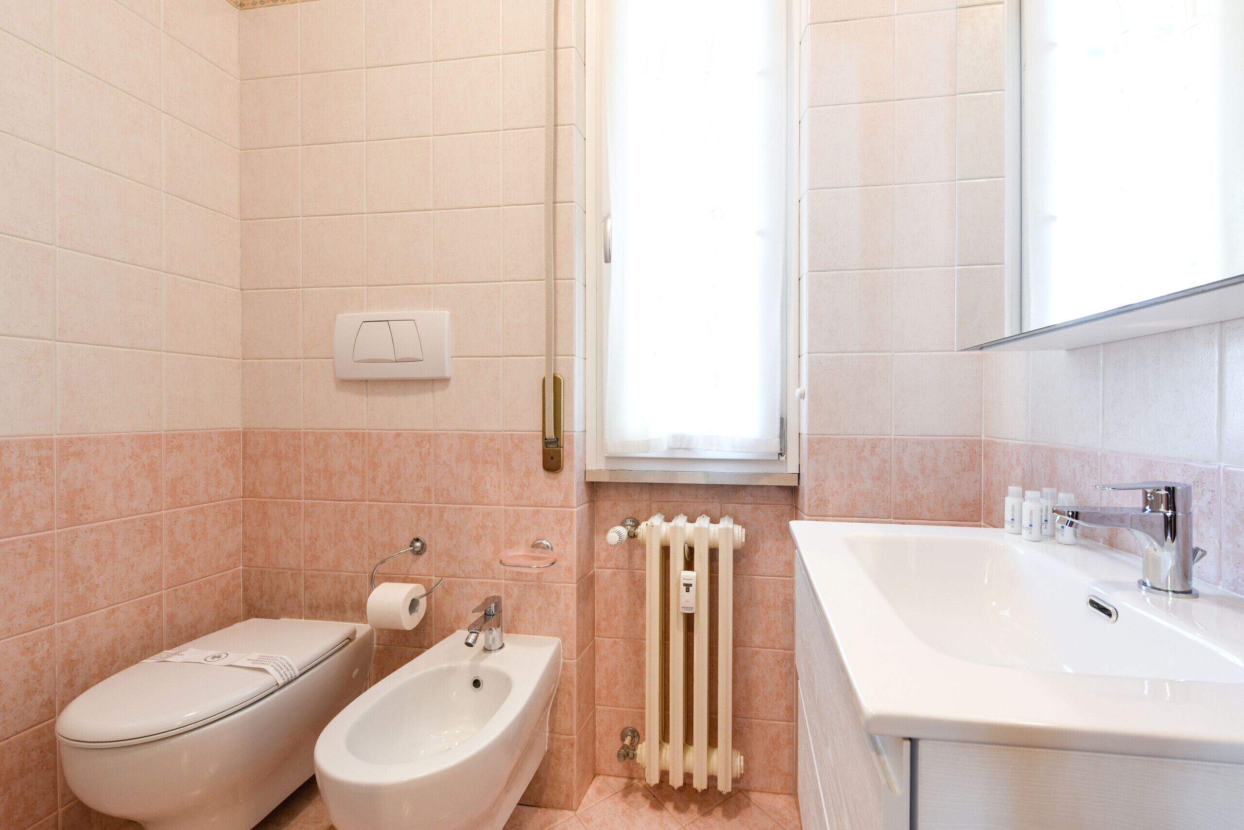 A modern bathroom with a toilet, bidet, and sink.