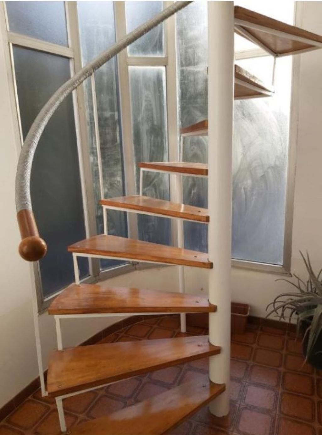 A spiral staircase with wooden steps and a metal handrail.