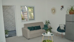 Een moderne woonkamer met een bank, een kleine ronde tafel en een kamerplant.
