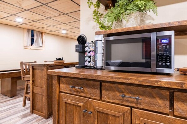 A kitchen with a microwave, coffee maker, and cabinets.