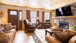 A cozy living room with a stone fireplace, wooden ceiling, and comfortable seating. - 4-bedroom cabin just 10 minutes from Adirondack Park (Thendara)