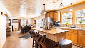 A spacious kitchen with wooden cabinets, a large island, and pendant lighting. - 4-bedroom cabin just 10 minutes from Adirondack Park (Thendara)