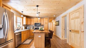 A kitchen with wooden cabinets, a central island, stainless steel appliances, and a wooden ceiling. - 4-bedroom cabin just 10 minutes from Adirondack Park (Thendara)