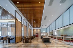 Un interior espacioso con techo alto, paneles de madera y una larga zona de comedor con mesas y sillas.