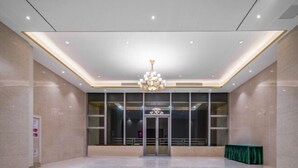 Spaziosa hall con un lampadario, una reception e un tavolo verde.