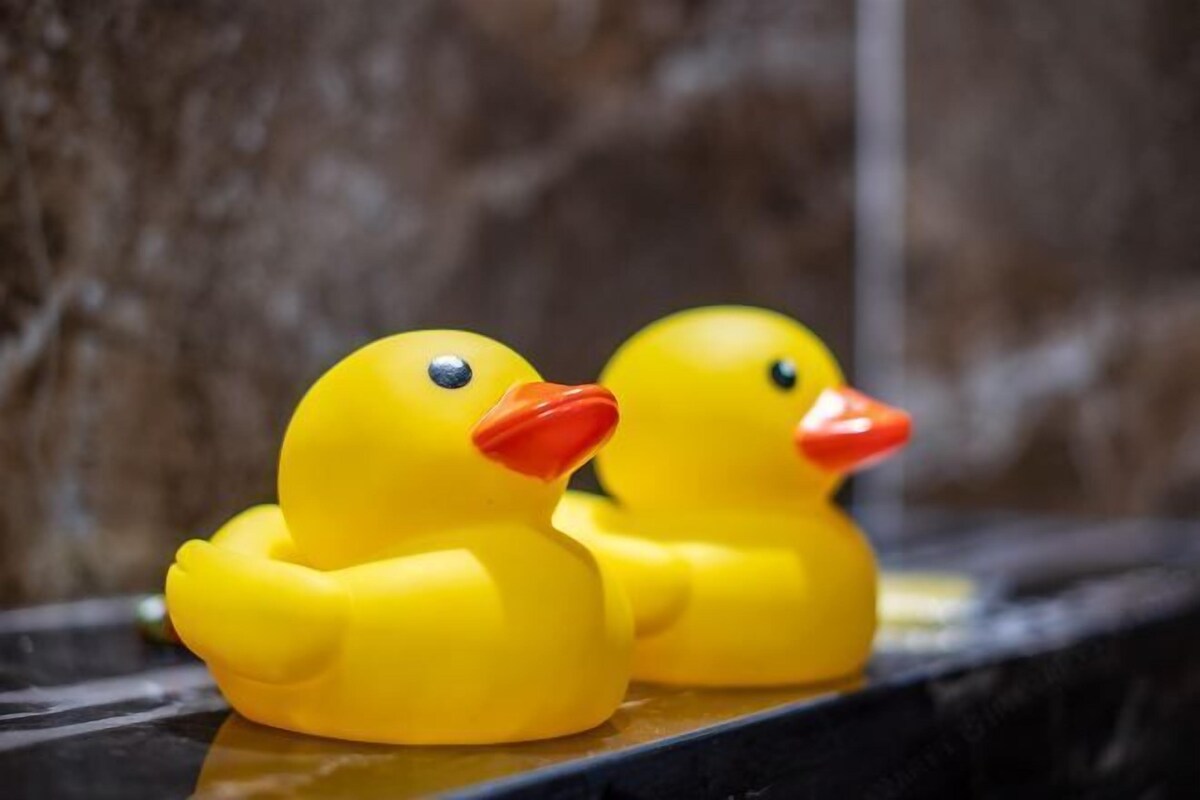 Two yellow rubber ducks on a reflective surface.