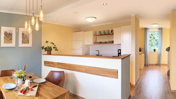 Eine moderne Küche mit weißen Schränken, einer Holzarbeitsplatte und einem Essbereich mit einem Holztisch und Stühlen.