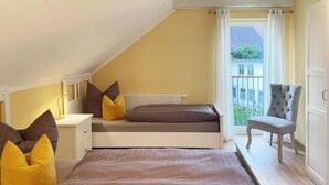 Ein Schlafzimmer mit schrägen Wänden, einem Bett mit brauner Bettwäsche, einem Nachttisch mit Lampe und einem Sessel.