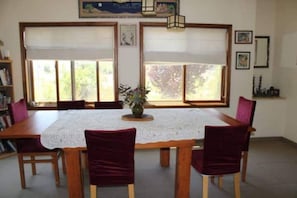 A dining area with a wooden table and chairs, lace tablecloth, and a vase with flowers. - Large yet Cozy Home in Golan (Golan)