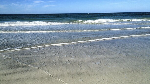 Ein Strand mit klarem, blauem Wasser und einem sandigen Ufer.