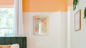 Een slaapkamer met een bed, een bureau, een stoel, een lamp en een lijst met een afbeelding aan de muur.