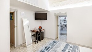 Ein Zimmer mit Schreibtisch, Stuhl und einem an der Wand befestigten Flachbildfernseher.