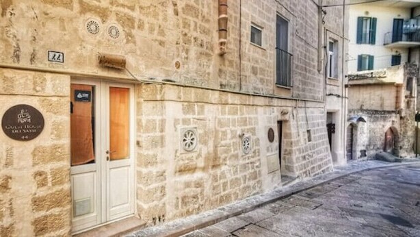 Une rue étroite bordée d’un bâtiment en pierre, avec une porte et une plaque.