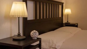 Une chambre d’hôtel avec un lit, deux tables de chevet et deux lampes.