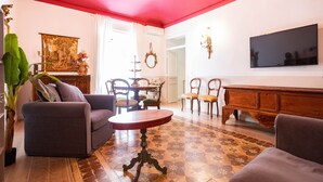 A living room with a red ceiling, a television mounted on the wall, and a patterned floor.