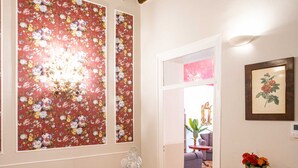 A dining area with a wooden table, a floral wallpaper, and a chandelier.