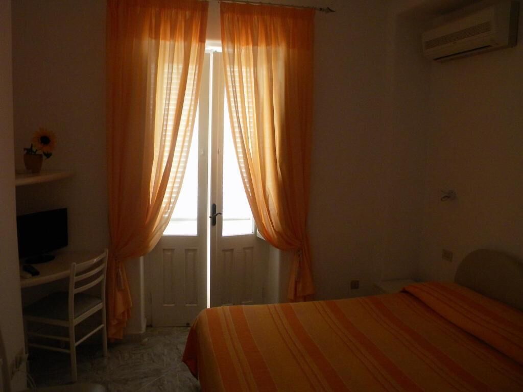 Un dormitorio con una cama, un escritorio con silla y una ventana con cortinas.
