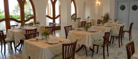 A dining area with round tables, chairs, and a tiled floor.
