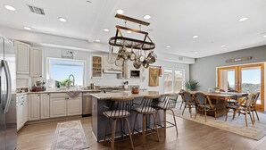 A modern kitchen with a central island, bar stools, and a hanging pot rack. - Mountaintop Ramona Home: Private Pool, Near Lake! (Ramona)