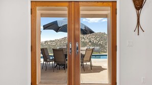 A sliding glass door leading to an outdoor patio with a pool and chairs. - Mountaintop Ramona Home: Private Pool, Near Lake! (Ramona)